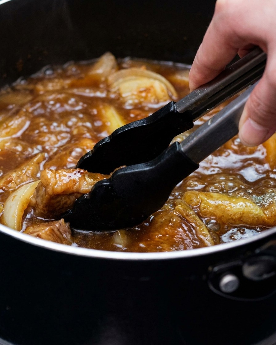 Une casserole de bouillon au curry avec du tofu et des oignons verts remuée avec une pince.