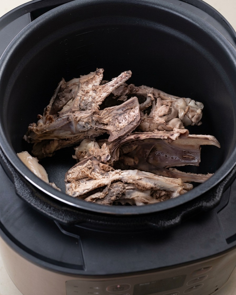 Os de poulet et aromates comme loignon et le gingembre à lintérieur de la cocotte-minute