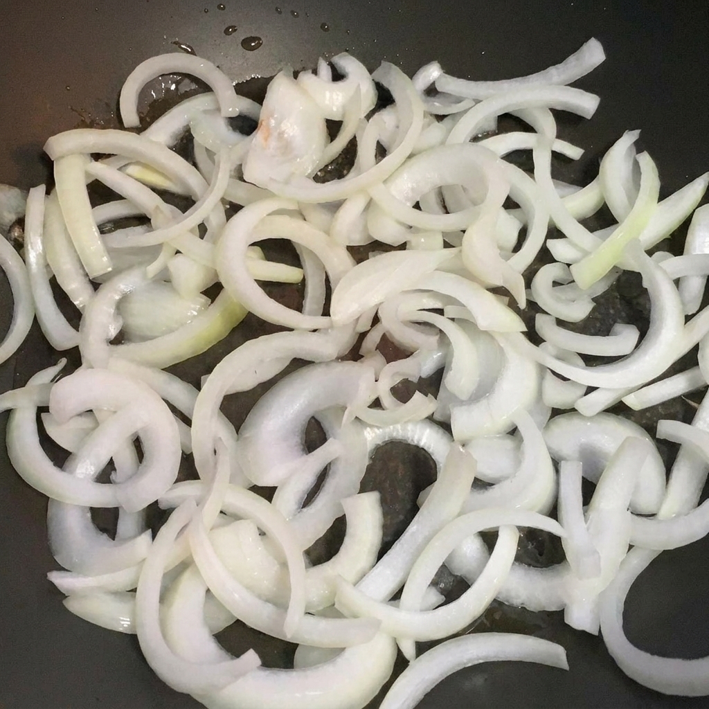 Tranches doignons cuisant dans une poêle jusquà devenir translucides.