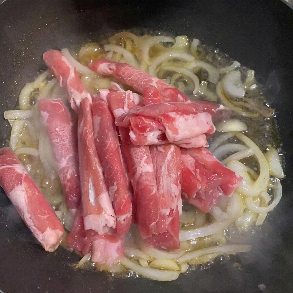 Tranches fines de bœuf ajoutées dans la poêle avec les oignons et leau.