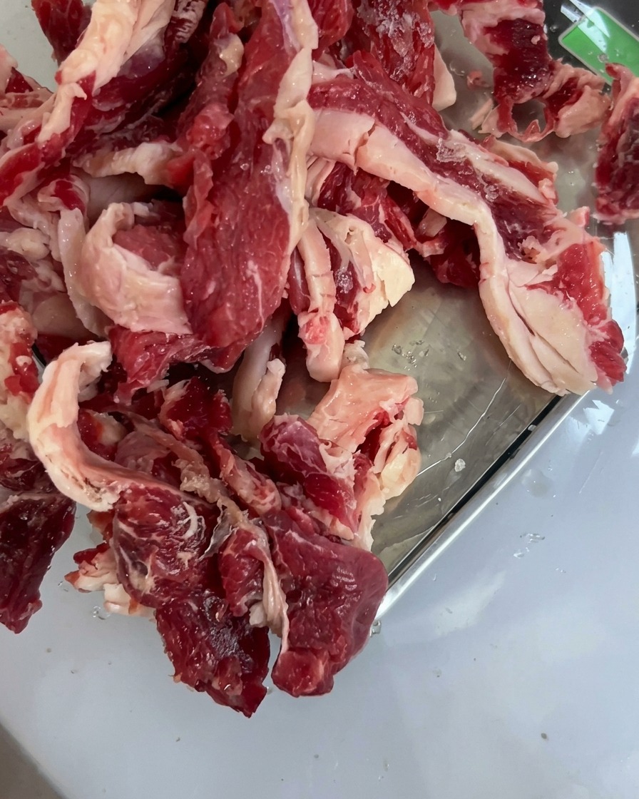 Morceaux de bœuf cru frais disposés proprement dans un plateau en acier inoxydable.