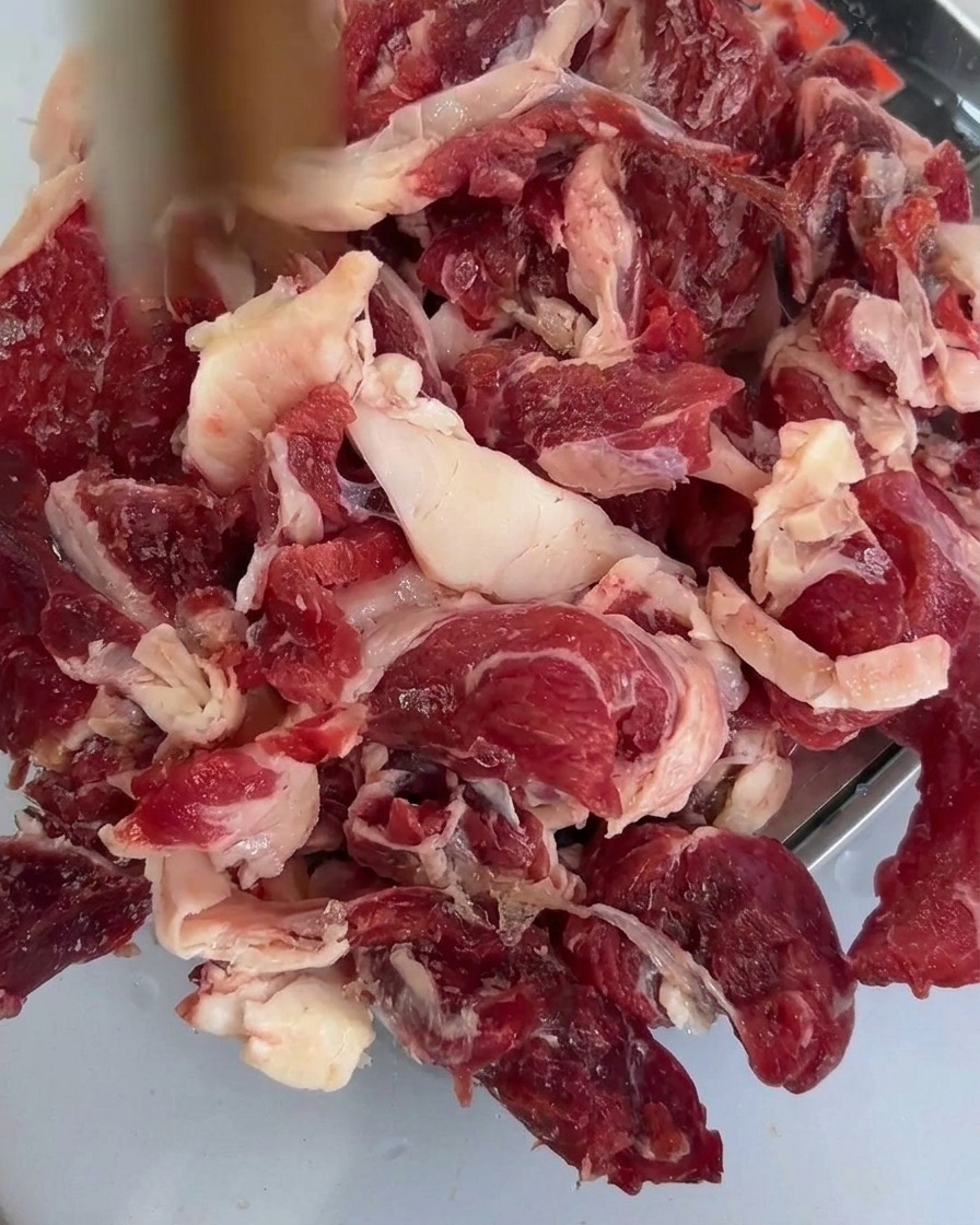 Champignons shiitakés fraîchement tranchés déposés sur le bœuf cru dans un plateau métallique.