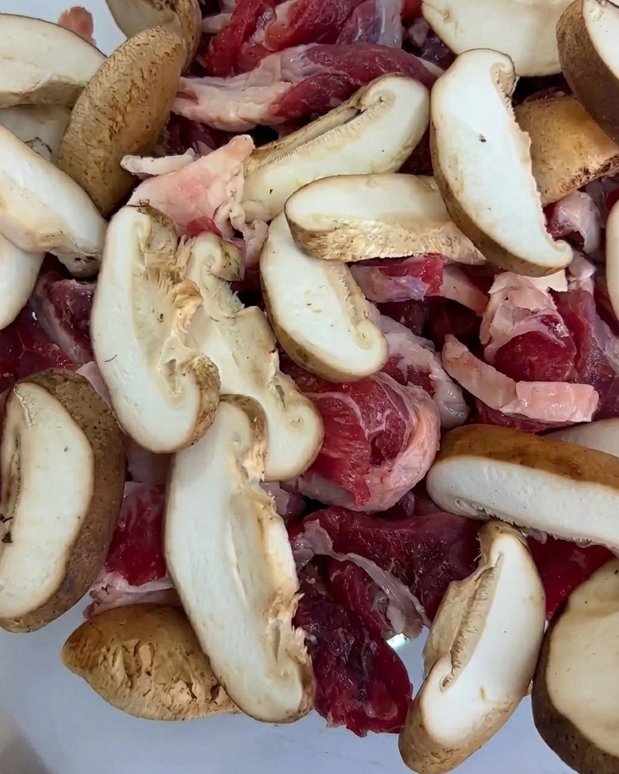 Morceaux de maïs miniature ajoutés au plateau, mélangés au bœuf et aux tranches de champignons.