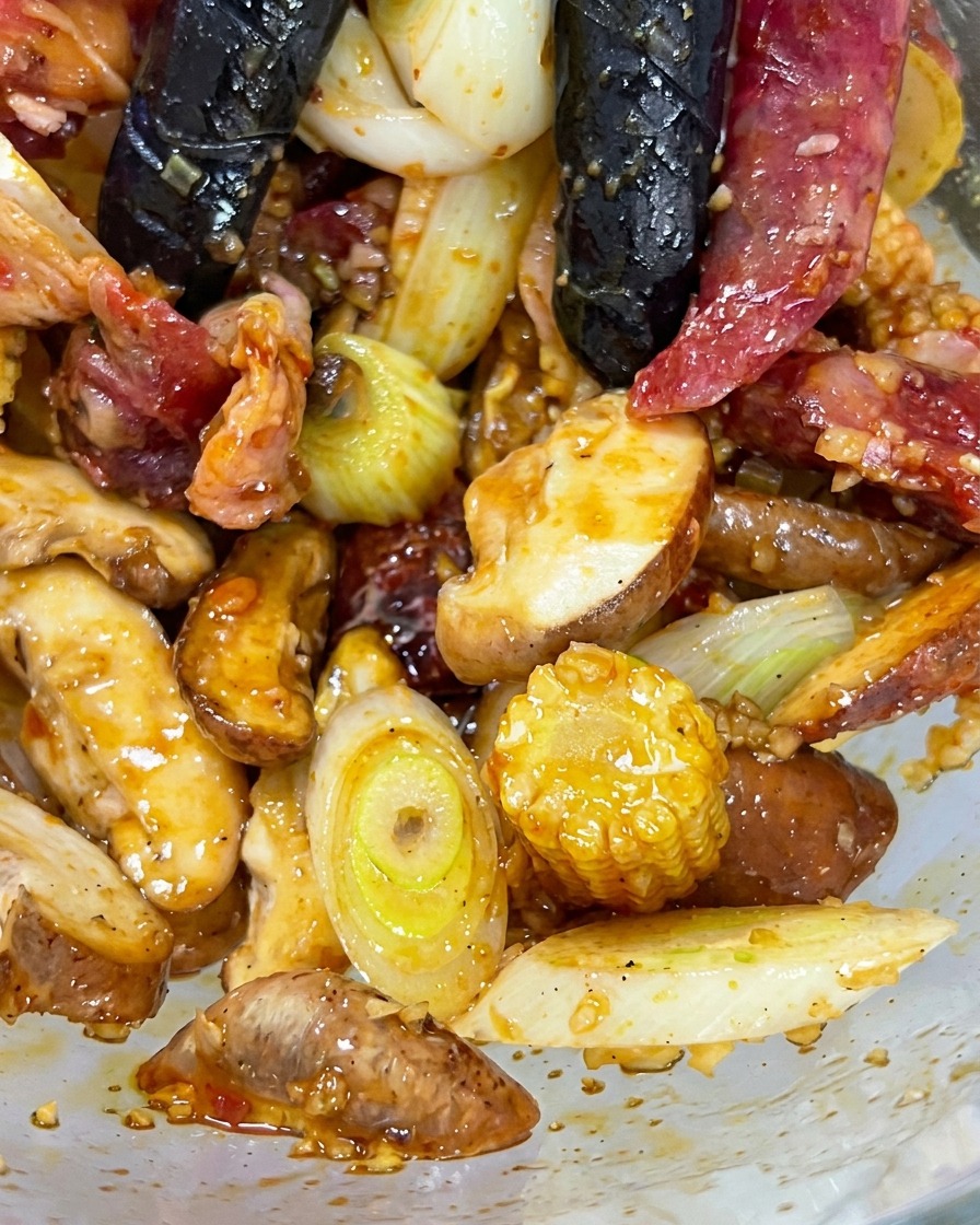Mains gantées mélangeant le bœuf, les champignons, le maïs et les aromates dans un bol en verre.