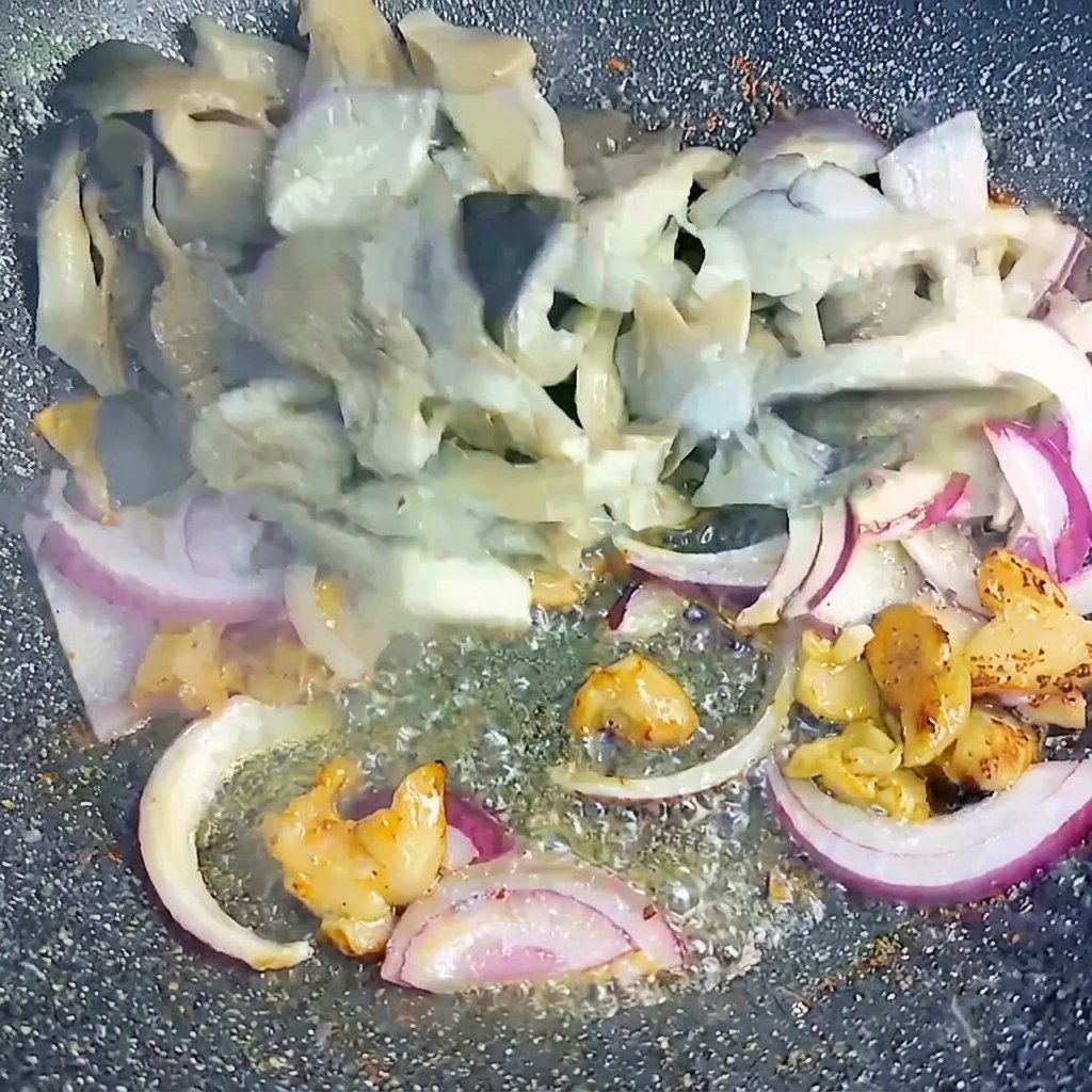 Pleurotes blanchis et oignons rouges émincés mélangés à la poitrine de porc dans le wok.