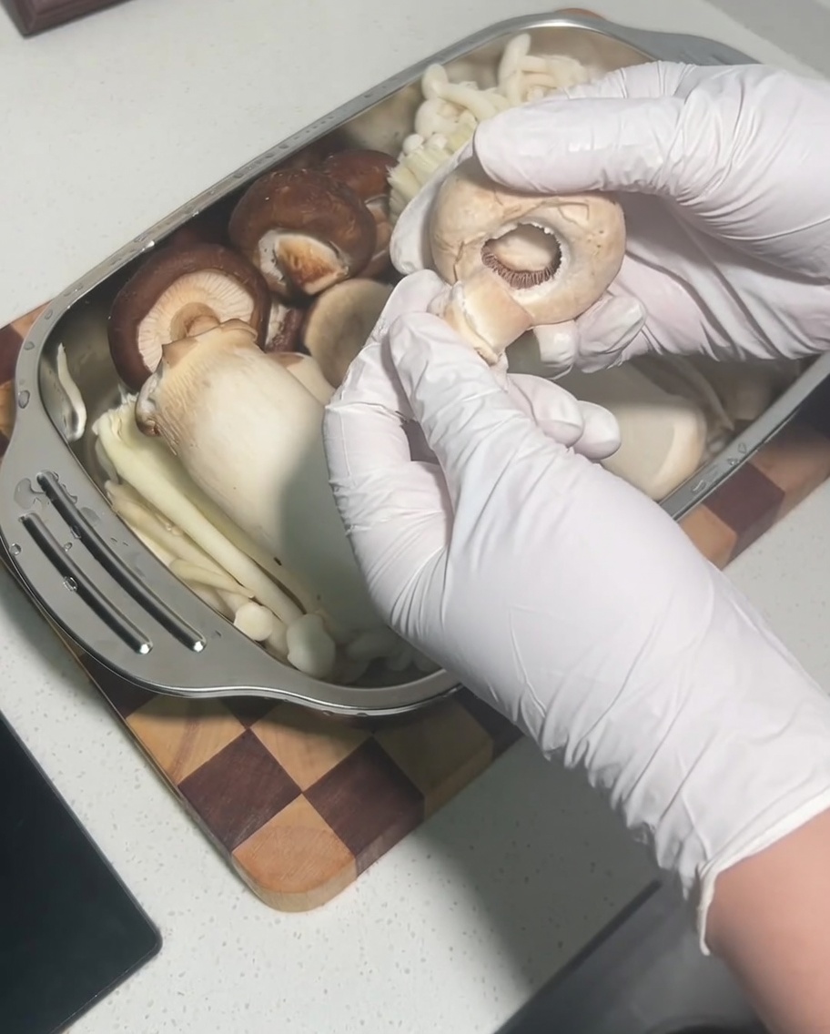 Une main retirant le pied dun chapeau de champignon shiitake cru entier.