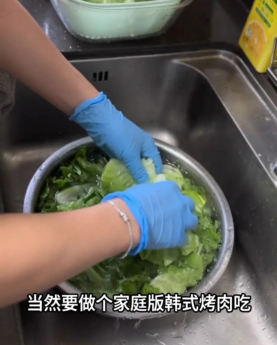 Feuilles de laitue verte fraîche en cours de lavage dans un grand bol en métal rempli deau.