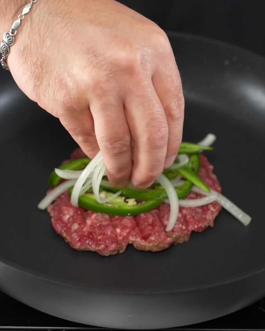 Rondelles de jalapeño frais et tranches doignon posées sur un steak de bœuf grésillant.