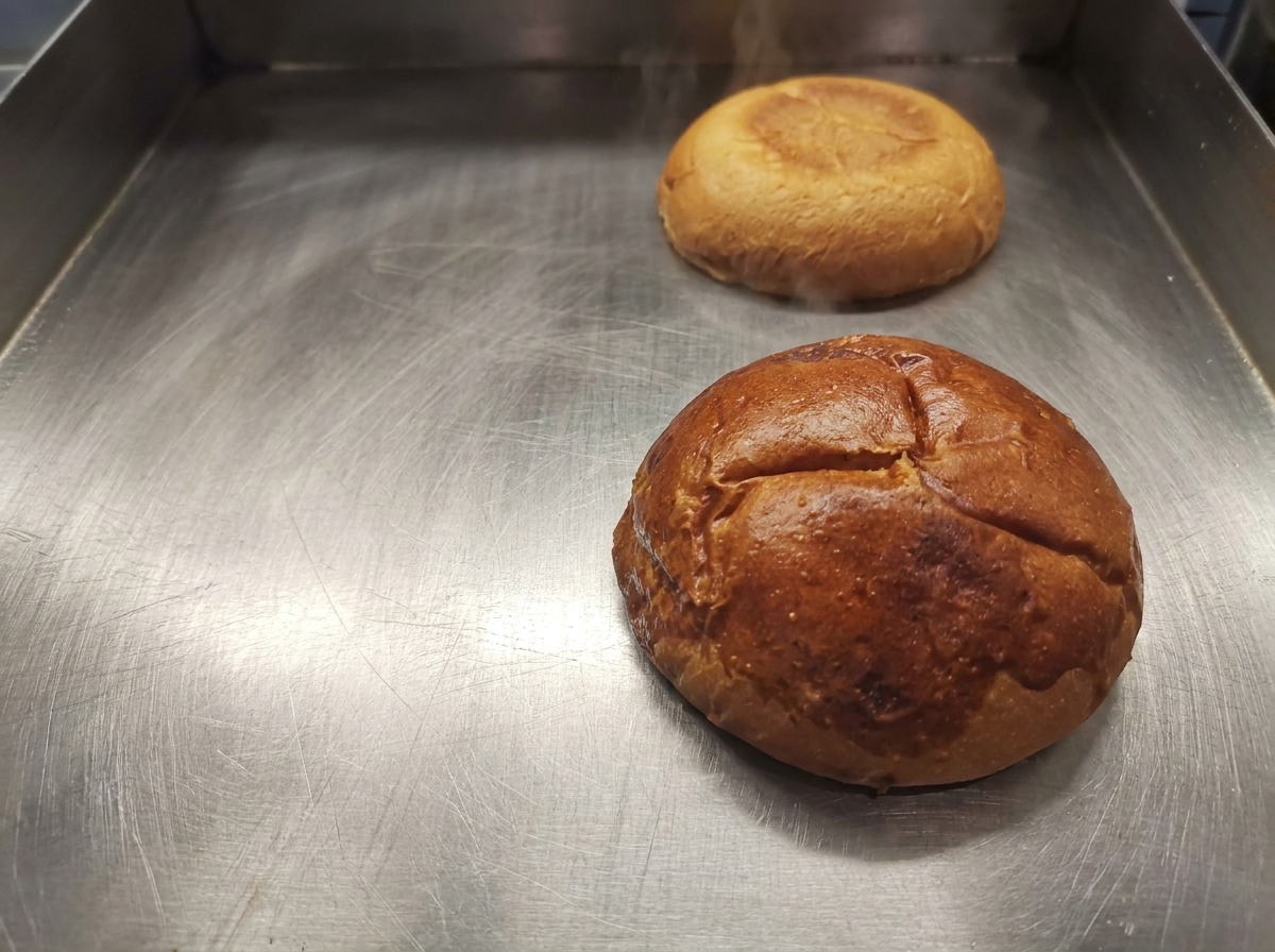 Moitiés de pain à burger dorées reposant sur une plaque de cuisson propre.