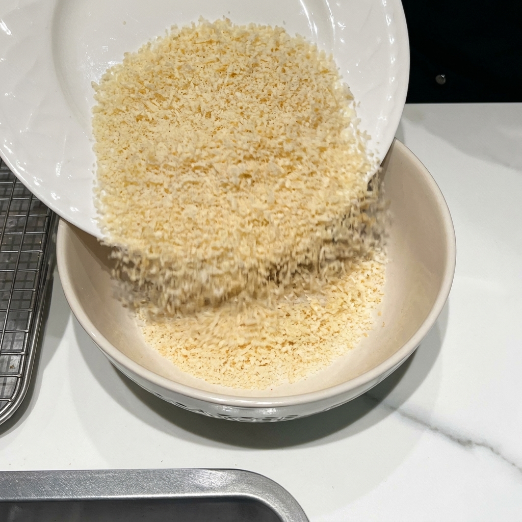 Un bol contenant de la chapelure, du parmesan râpé et diverses épices en cours de mélange.