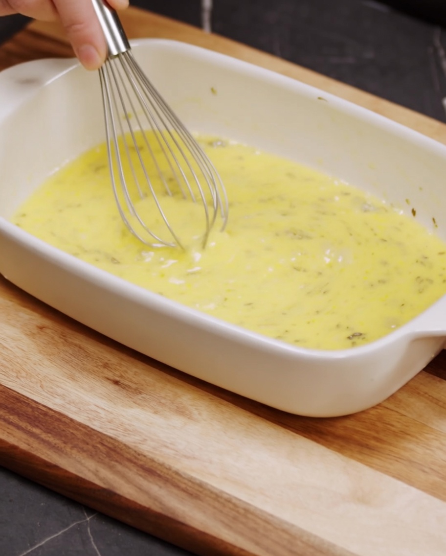 Fouet mélangeant de la chapelure, du parmesan râpé et du poivre dans un plat en céramique.