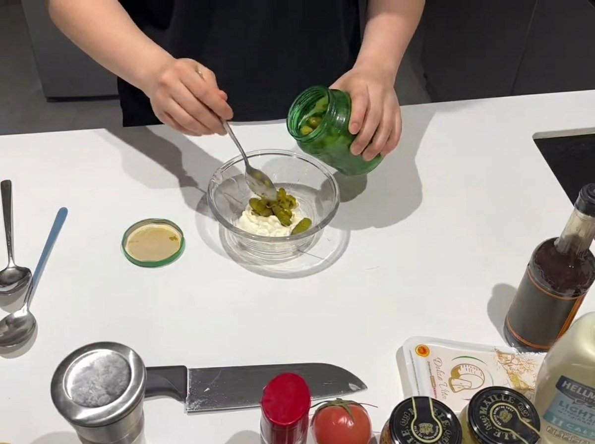 Une cuillerée de relish sucré ajoutée dans un bol contenant de la mayonnaise crémeuse.
