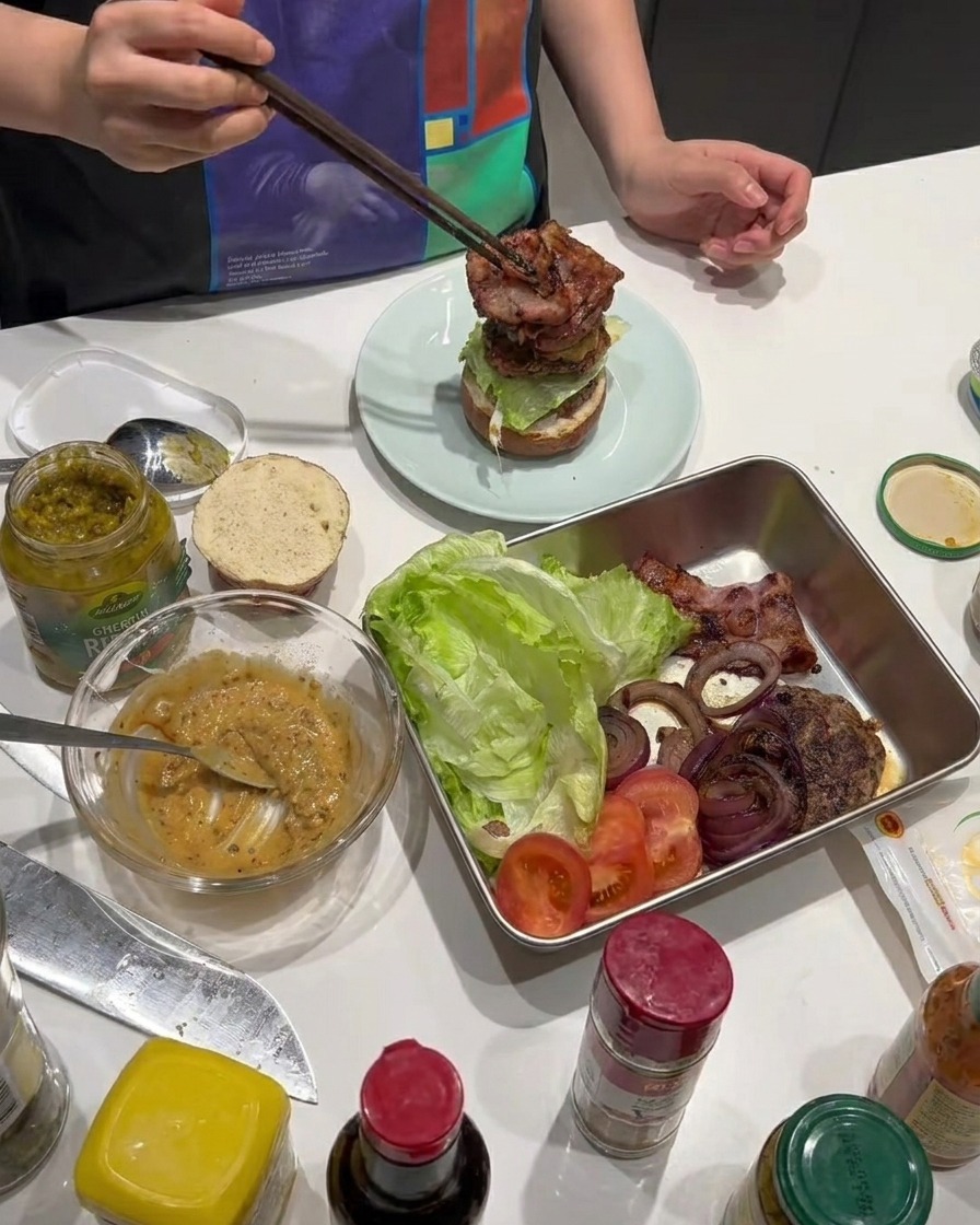 Tranches de bacon croustillantes ajoutées au montage du burger.