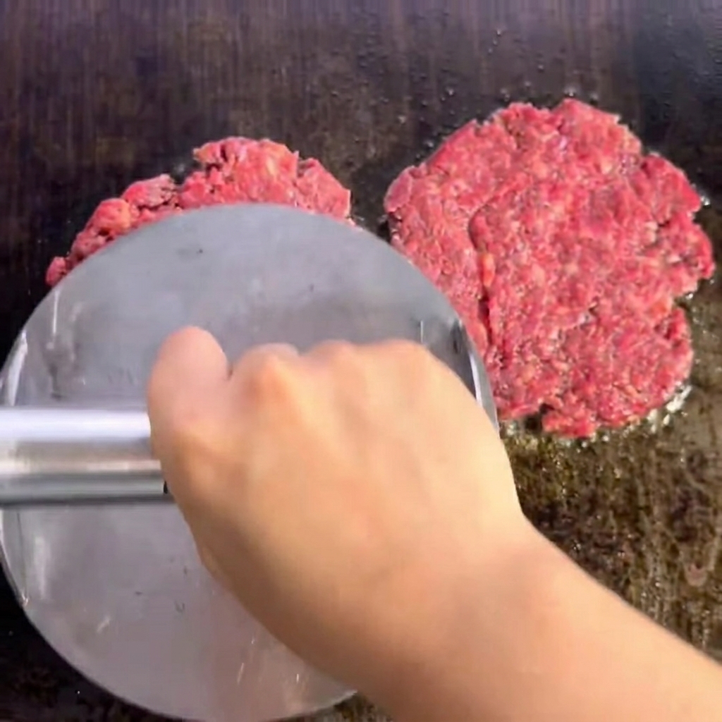 Deux steaks de bœuf assaisonnés saisissant sur le gril, présentant une croûte bien dorée.