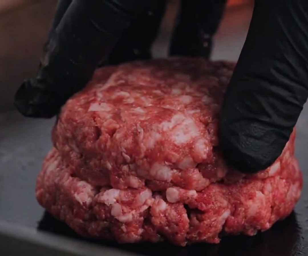 Un steak de bœuf Angus cru pressé sur un grill chaud.