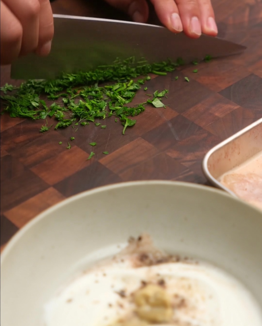 Ciboulette et persil frais ajoutés au bol de yaourt et doignon.