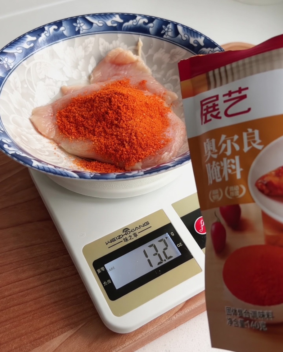 Poudre de marinade Orléans pesée dans un bol contenant un morceau de poulet cru.