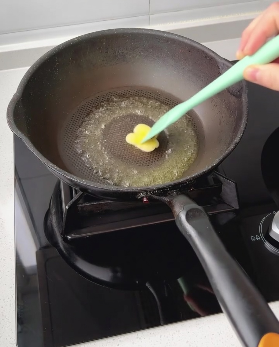 Un petit morceau de beurre fondant dans une poêle antiadhésive sombre et étalé avec une spatule.