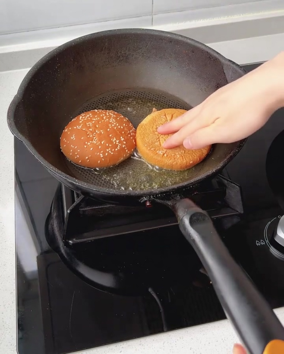 Moitiés de pain à burger toastées face contre poêle avec du beurre fondu.
