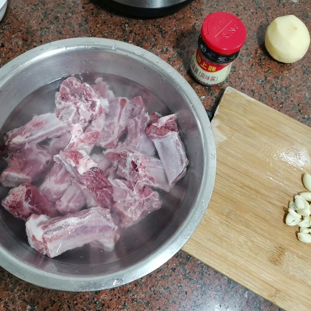 Travers de porc crus immergés dans un grand bol en métal rempli deau froide.