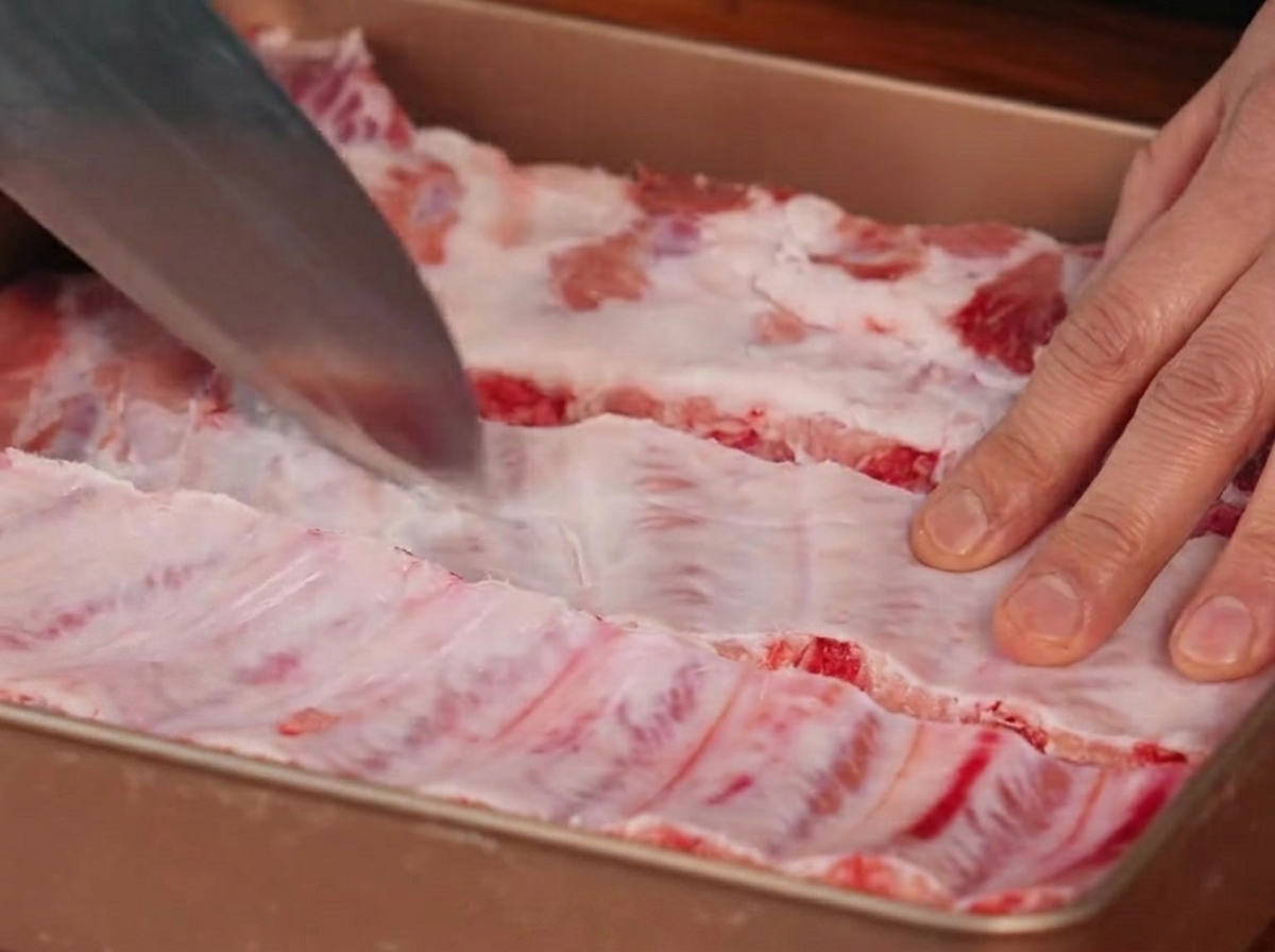 Un couteau incisant la membrane située au dos des travers de porc.