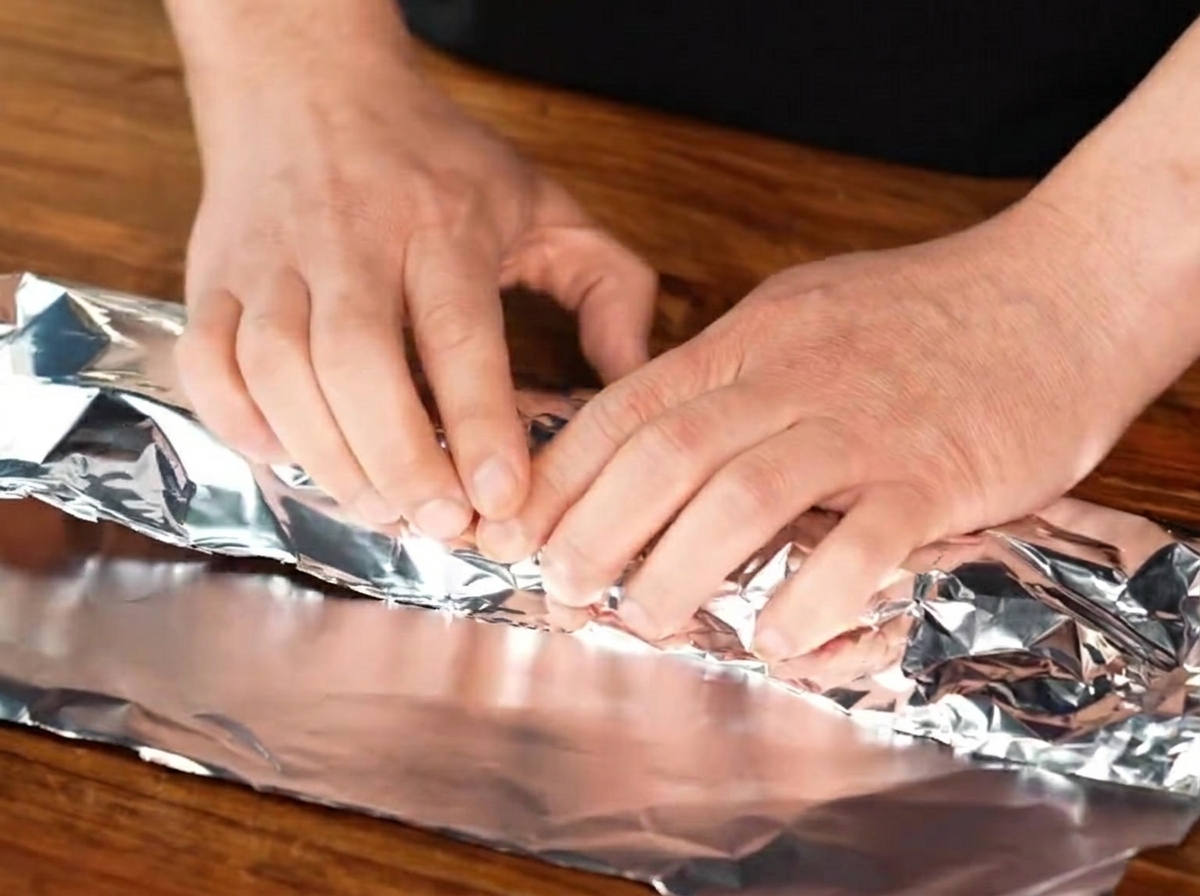 Travers de porc assaisonnés hermétiquement enveloppés dans une feuille de papier aluminium.