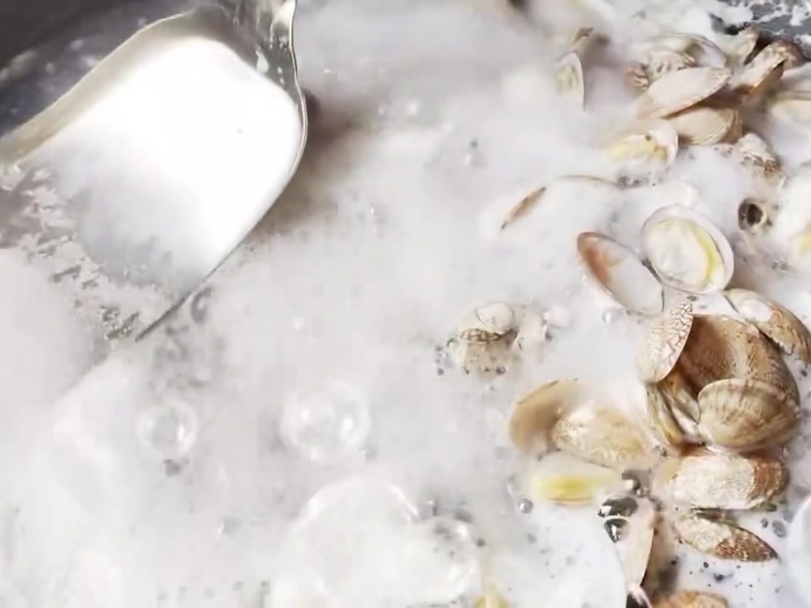 Une écumoire en métal retirant lécume à la surface de leau bouillante.