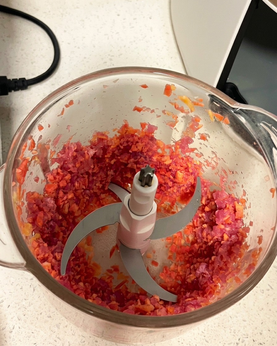 Mélange de porc et carotte haché avec une texture uniforme dans le bol du mixeur.