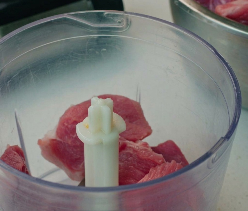 Morceaux de porc hachés dans le bol dun robot culinaire.