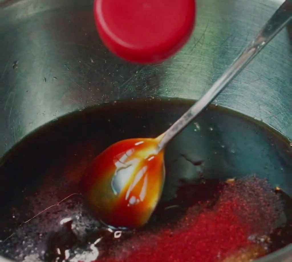 Porc haché mélangé avec divers assaisonnements liquides dans un bol en inox.