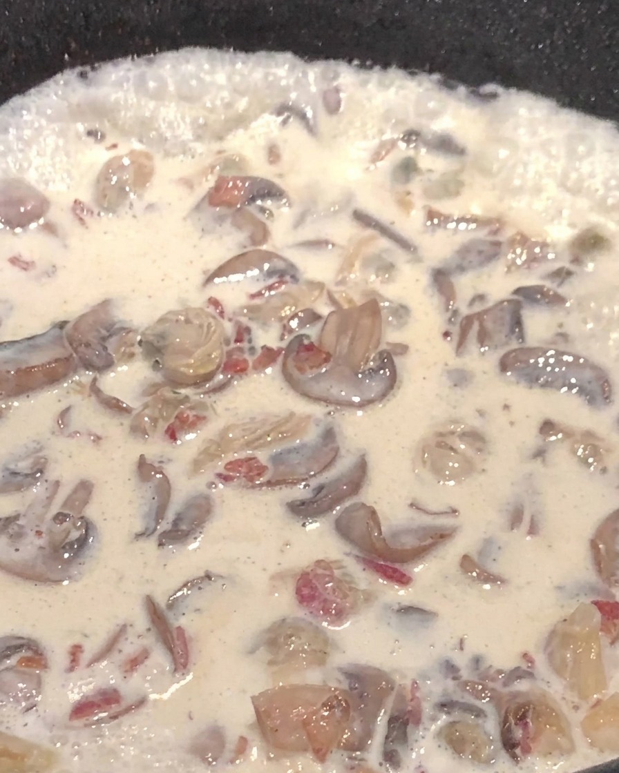 Préparation crémeuse aux champignons et pommes de terre dans la poêle.