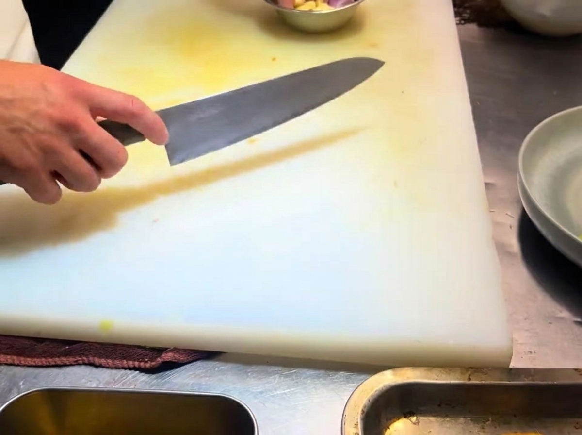 Gousses dail finement tranchées sur une planche à découper blanche.