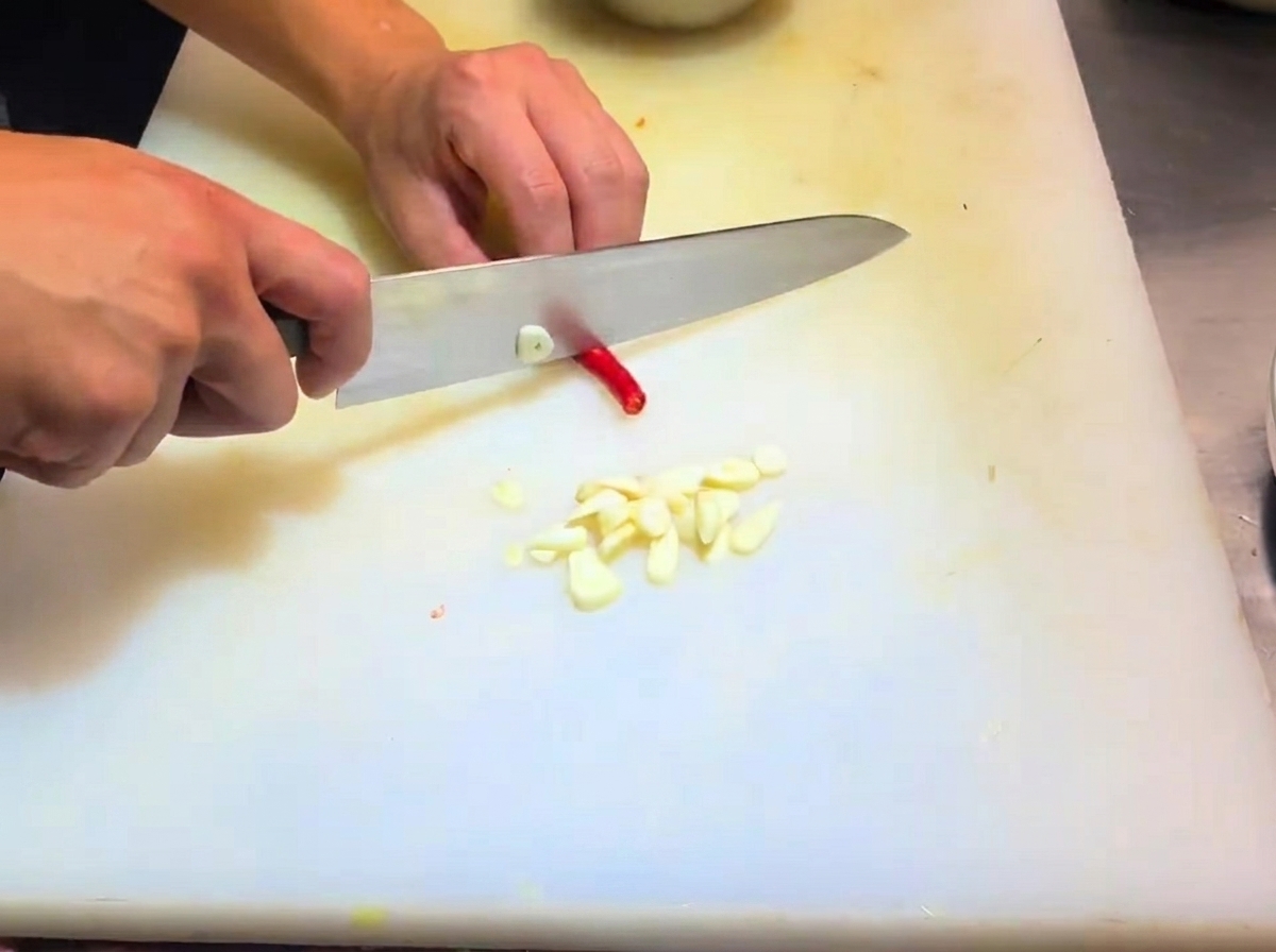 Échalotes et morceaux de piment préparés sur une planche à découper.