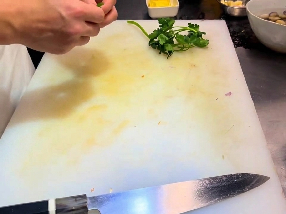 Feuilles et tiges de persil séparées sur une planche à découper.