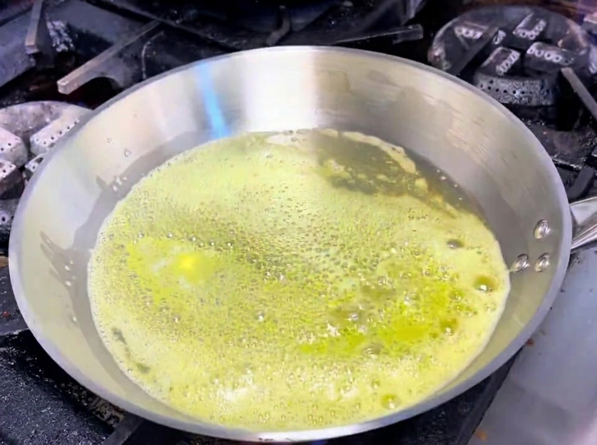 Ail et échalotes grésillant dans le beurre fondu dans une poêle.