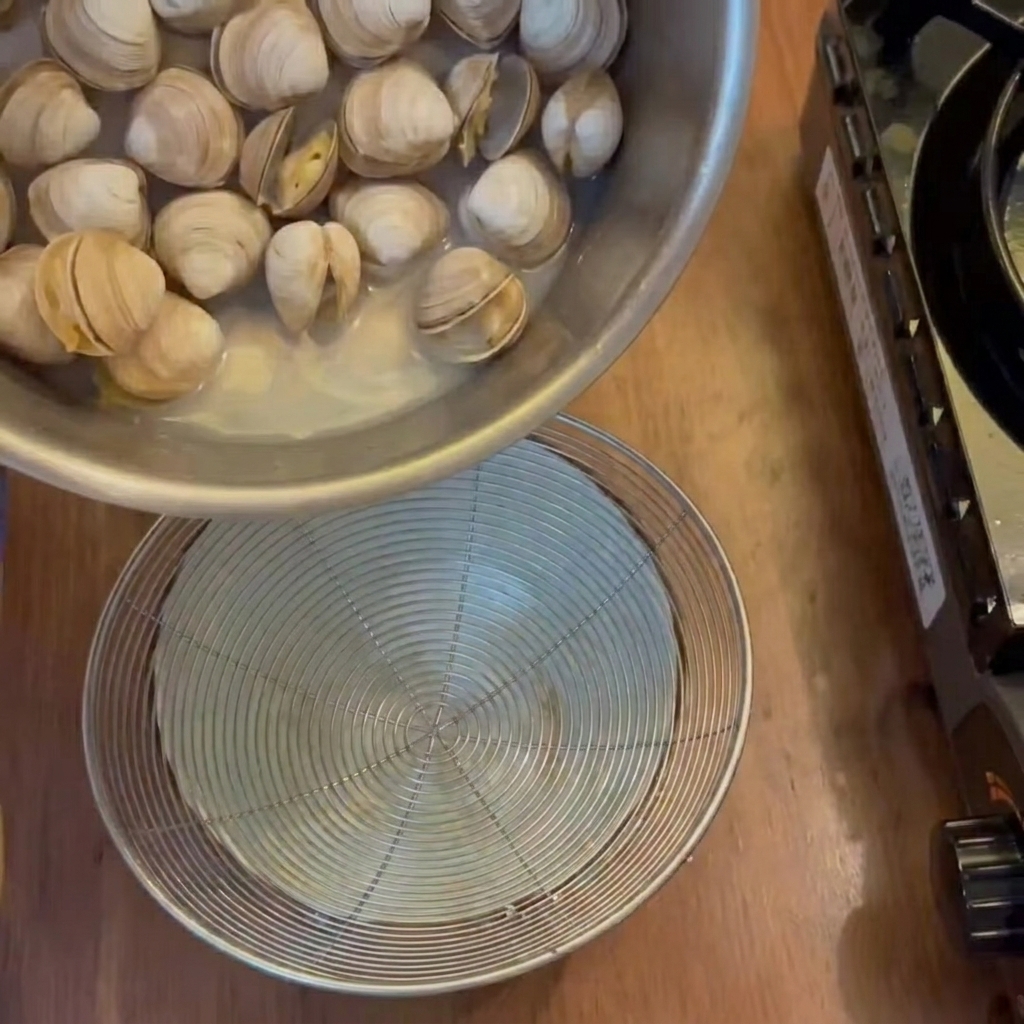 Le bouillon liquide filtré des palourdes cuites dans un bol en dessous.