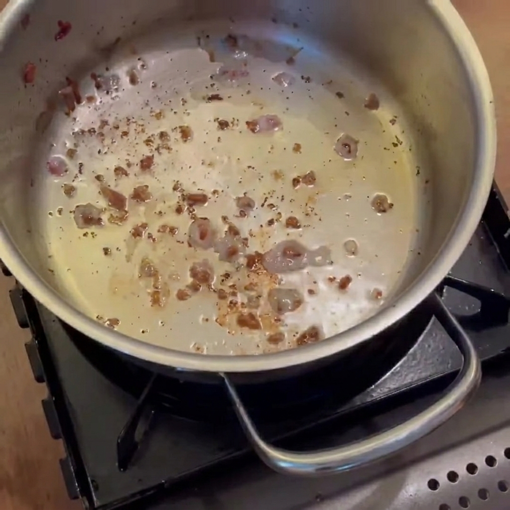 Oignons, carottes et pommes de terre revenant dans la casserole avec la graisse de bacon jusquà ce quils soient translucides.