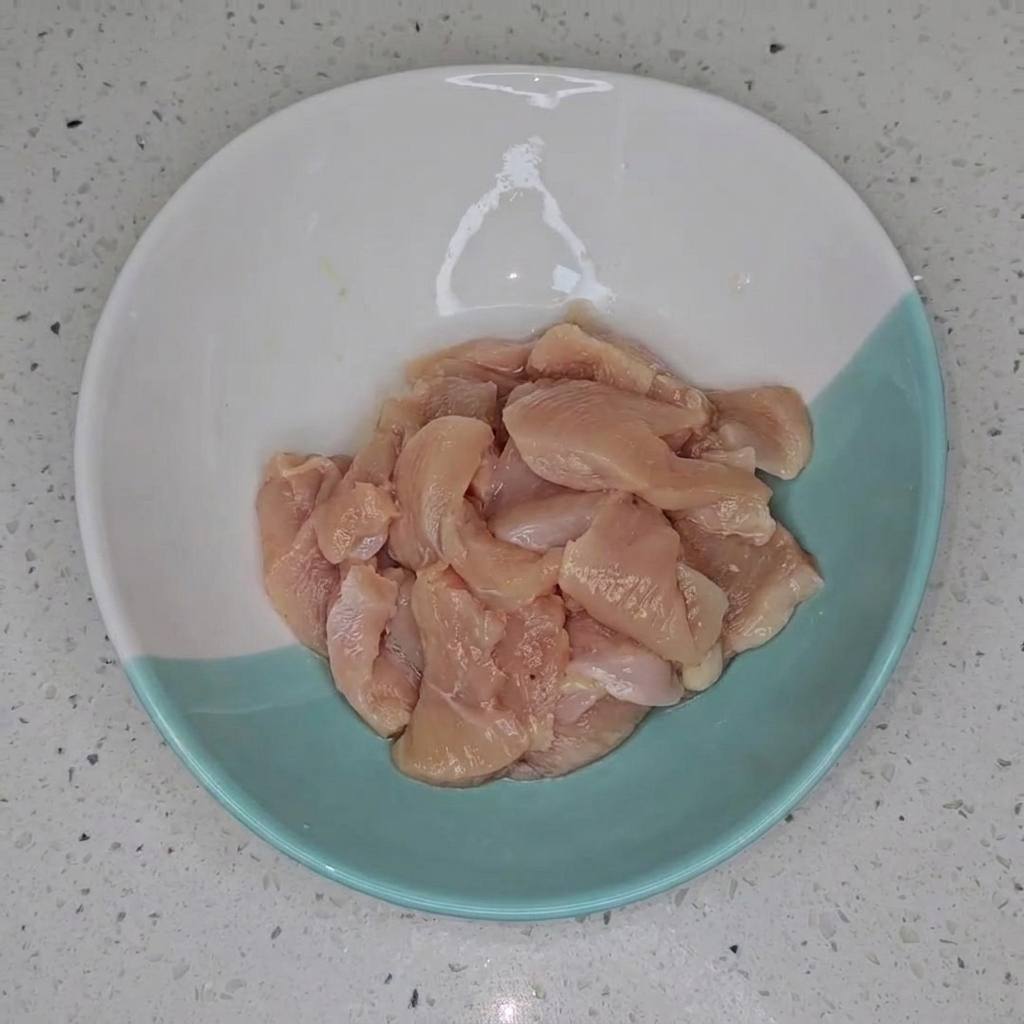 Dés de blanc de poulet dans un bol bicolore, prêts pour la cuisson.