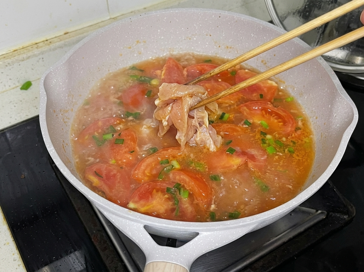Morceaux de poulet plongés dans le bouillon de tomate frémissant avec des baguettes.
