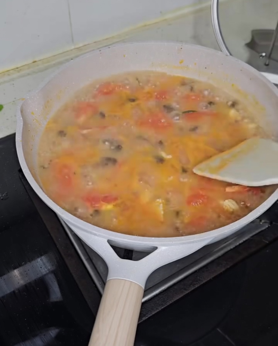 Ciboule ciselée parsemée sur une marmite de soupe au poulet et gnocchis fumante.