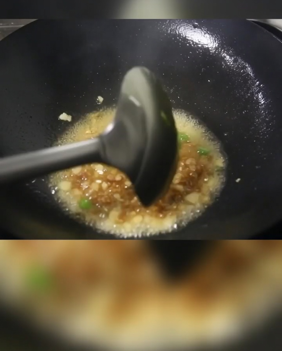 Cébettes, dés de porc et cubes de pommes de terre en train de cuire dans un wok huilé.