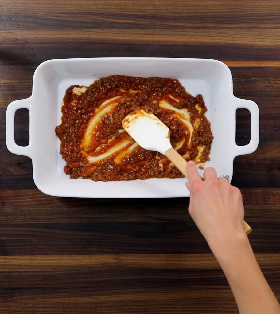 Gros plan sur un plat à four montrant les couches de sauce, de pâtes et de béchamel.