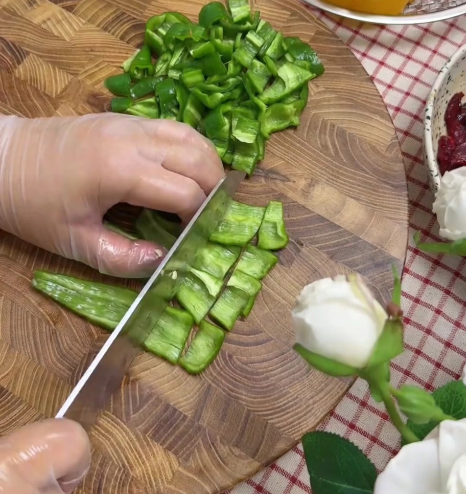 Poivrons et oignon rouge coupés en petits morceaux sur une planche à découper.