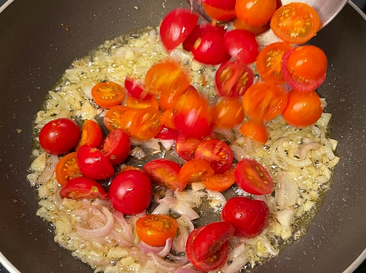 Aromates sautés et tomates cerises cuisant ensemble dans une poêle.