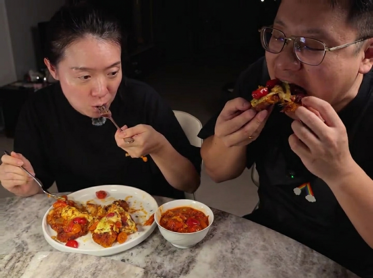 Mozzarella râpée saupoudrée sur les escalopes de poulet couvertes de sauce tomate dans une poêle.
