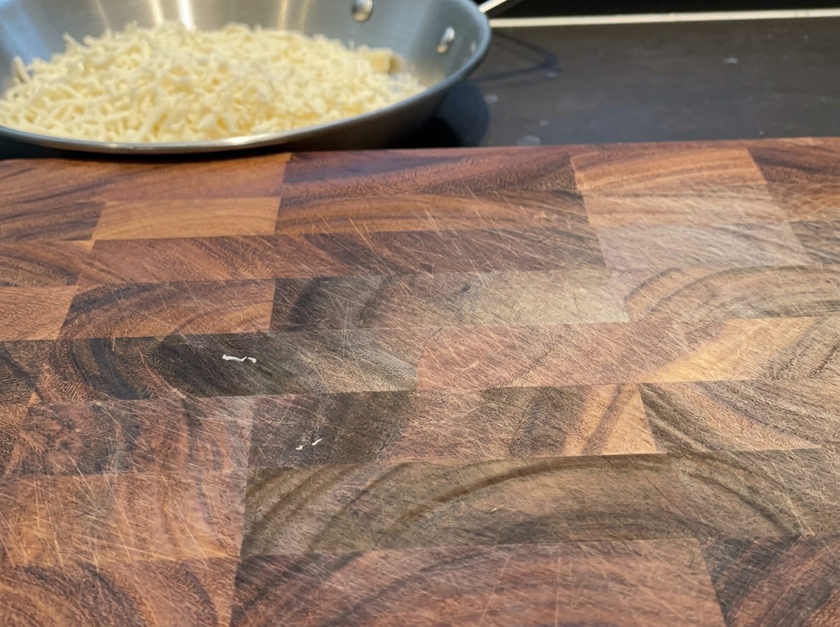 Tranches de cheddar coupées en fines lamelles uniformes sur une planche à découper en bois.