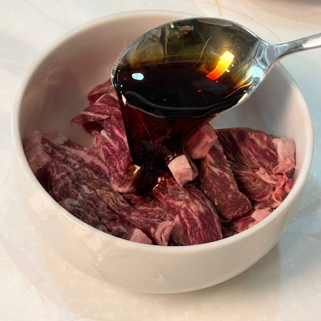 Sauce soja versée dune cuillère dans un bol contenant des lanières de bœuf cru et dautres assaisonnements.