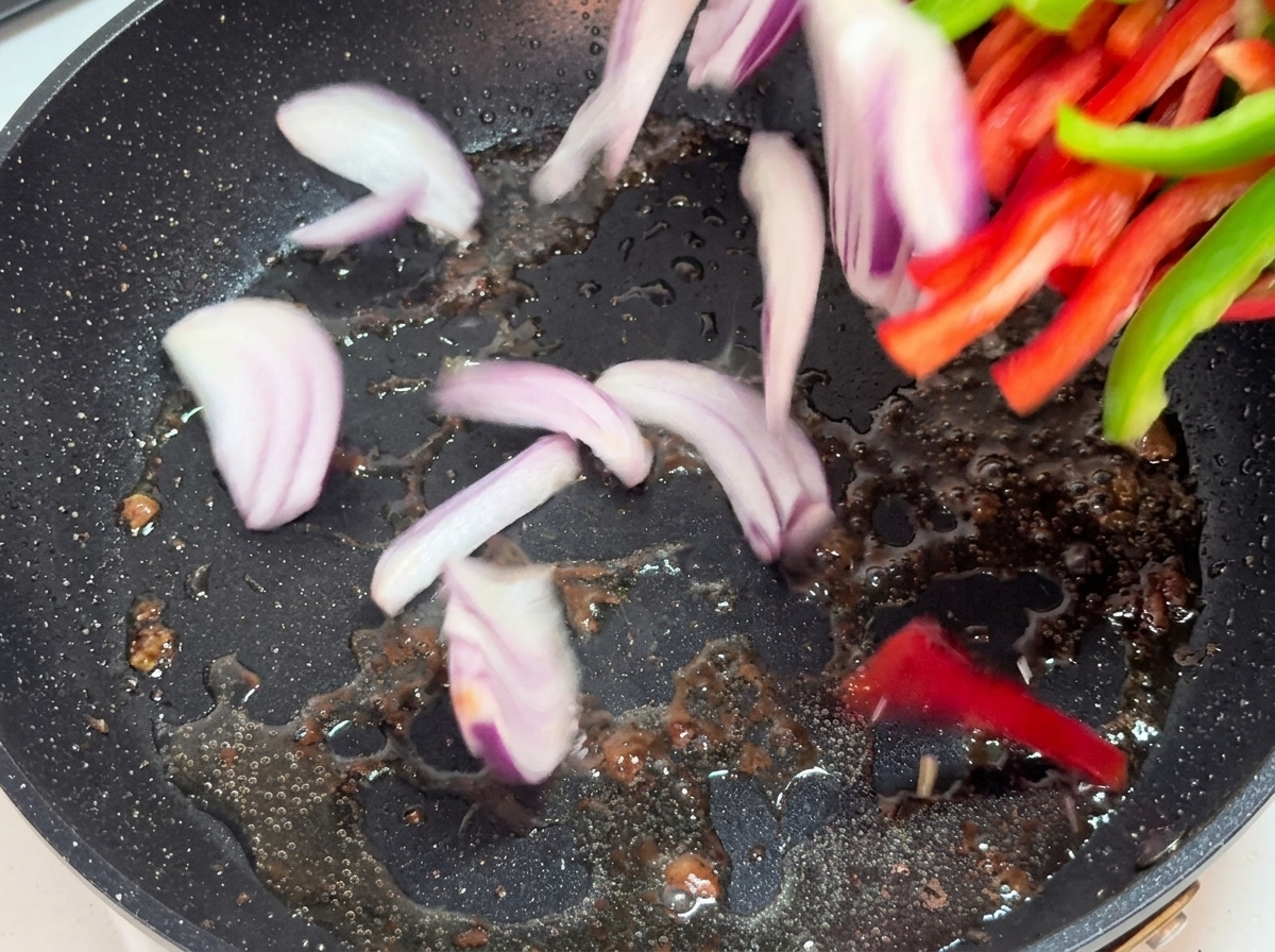 Lanières doignons et de poivrons sautant dans une poêle chaude.