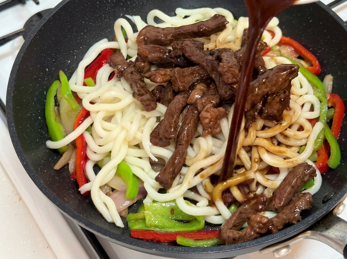 Sauce au poivre noir versée sur les ingrédients sautés.