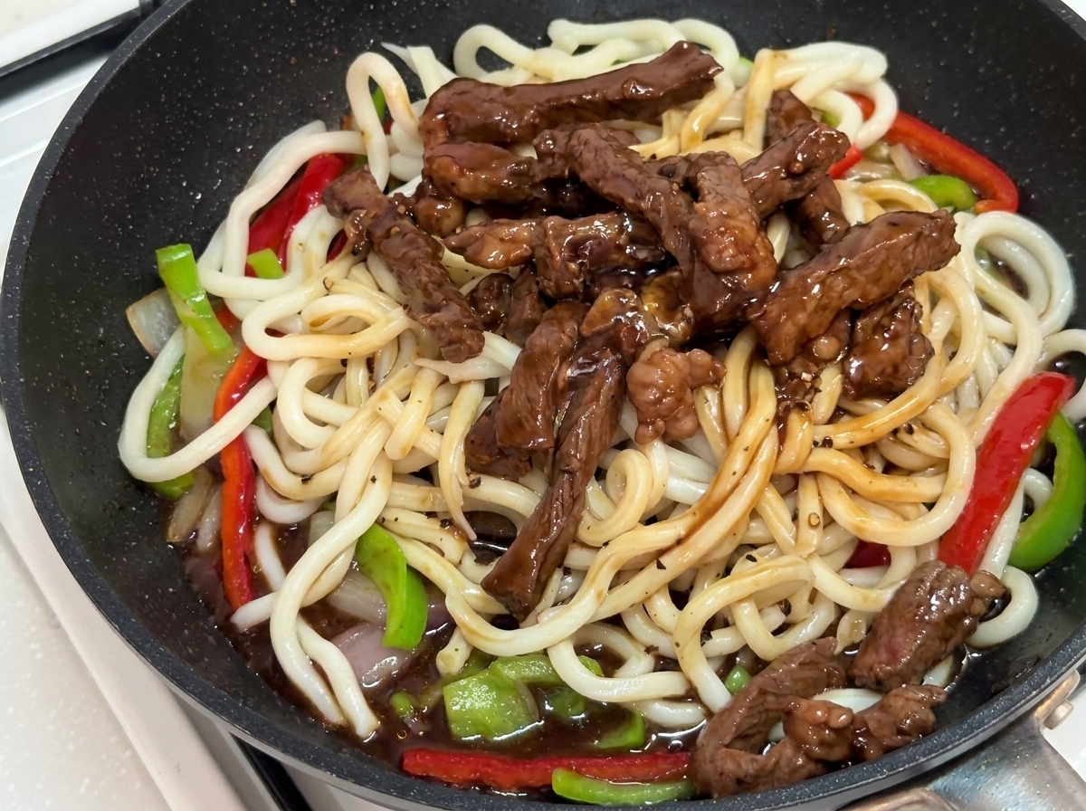 Sauté mélangé à laide de pinces dans la poêle jusquà ce quil soit bien enrobé de sauce.